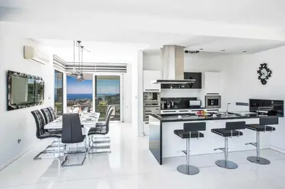 a white kitchen with black chairs and a table at Villa Pallas KO1 in Protaras