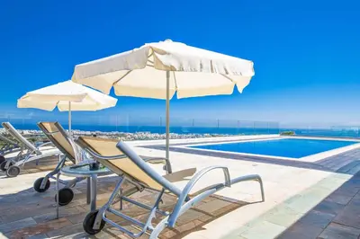 a table with an umbrella and chairs next to a swimming pool at Villa Pallas KO1 in Protaras