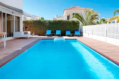 a swimming pool with blue chairs next to a house at Velomar Villa in Paralimni