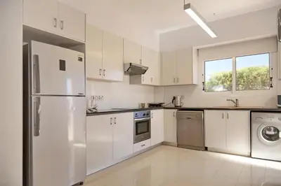 a kitchen with white cabinets and a refrigerator at Velomar Villa in Paralimni