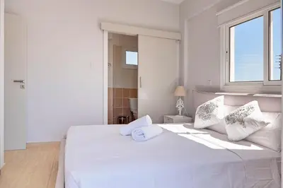 a white bedroom with a large white bed with a window at Velomar Villa in Paralimni