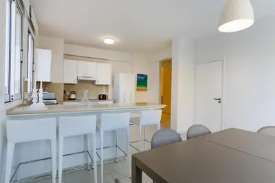 a kitchen with white cabinets and a table and chairs at Pernera Gardens Villa in Protaras
