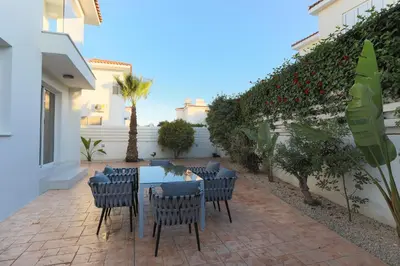 a patio with a table and chairs in a yard at Pernera Gardens Villa in Protaras