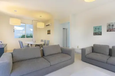 a living room with two couches and a table at Pernera Gardens Villa in Protaras