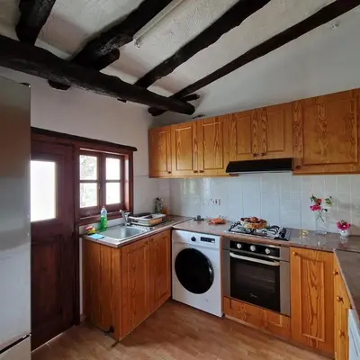 a kitchen with wooden cabinets and a white stove top oven at THE ROCK HOUSE - Beautiful countryside with mandarins oranges and olive trees,. Near Limassol at Eptagonia village. in Ephtagonia
