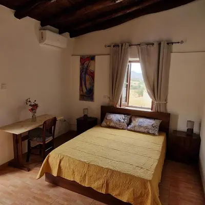 a bedroom with a large bed and a window at THE ROCK HOUSE - Beautiful countryside with mandarins oranges and olive trees,. Near Limassol at Eptagonia village. in Ephtagonia