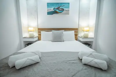 a bedroom with a large white bed with two lamps at Tsolias Apartments in Protaras