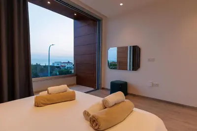 a bedroom with a bed and a large window at Napa Hills Seaview Villas - Iris in Ayia Napa