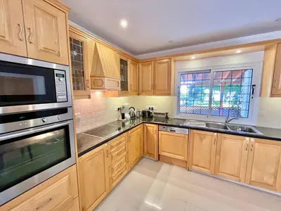 a kitchen with wooden cabinets and stainless steel appliances at Dream Beachfront Bungalow in Limassol