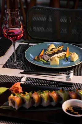 a table with a plate of food and a glass of wine at NYX Hotel Limassol in Limassol