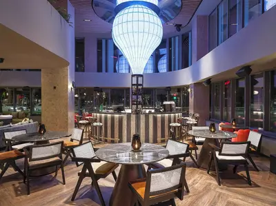 a restaurant with tables and chairs and a large chandelier at NYX Hotel Limassol in Limassol