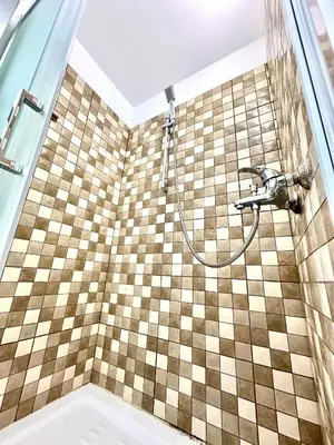 a bathroom with a shower with a checkerboard tile wall at Harbour Seaside Escape in Ayia Napa