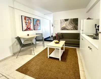 a kitchen and living room with a table and a refrigerator at Harbour Seaside Escape in Ayia Napa