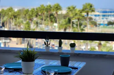a table with plates and plants on a balcony at Prime Beachfront Apartment on Larnaca Finikoudes in Larnaka