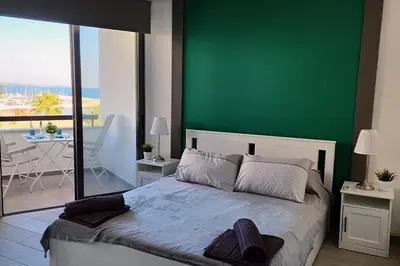 a bedroom with a green wall with a bed and a balcony at Prime Beachfront Apartment on Larnaca Finikoudes in Larnaka