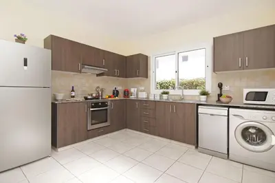 a kitchen with wooden cabinets and a white refrigerator at Nissi Dreams Villa in Ayia Napa