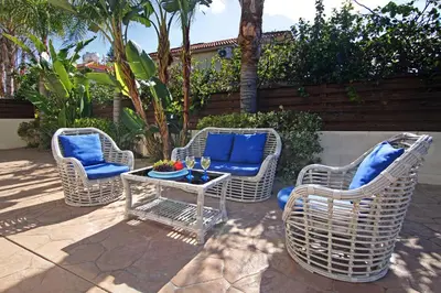 three wicker chairs and a table on a patio at Nissi Dreams Villa in Ayia Napa
