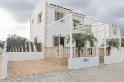 a white house with a palm tree in front of it at Blue Crystal Seaview in Protaras