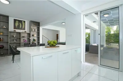 a kitchen with white cabinets and a living room at Villa Catalina in Ayia Napa