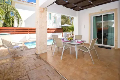 a patio with a table and chairs and a pool at Villa Mandy in Protaras