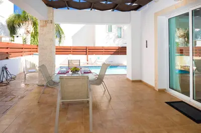 a living room with a table and chairs and a pool at Villa Mandy in Protaras