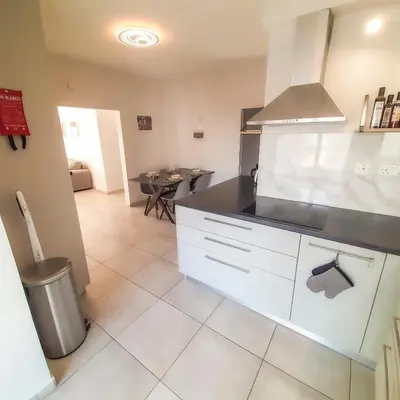 a kitchen with white cabinets and a dining room with a table at Sea Breeze Central, 2bed in Limassol
