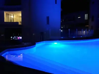 a swimming pool lit up in blue at night at Anamor apartment 408 in Larnaka