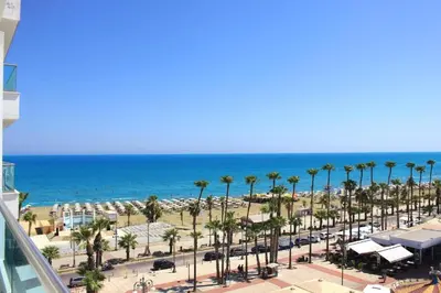a view of a beach with palm trees and the ocean at Anamor apartment 408 in Larnaka
