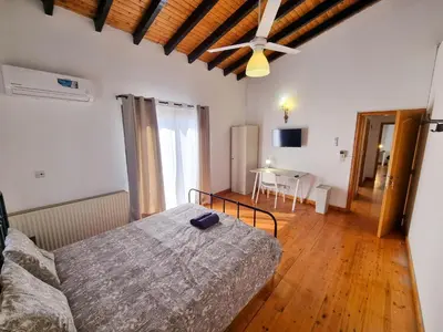a bedroom with a bed and a table and a ceiling fan at Mountains Retreat Rooms & Suites in Ayios Theodhoros