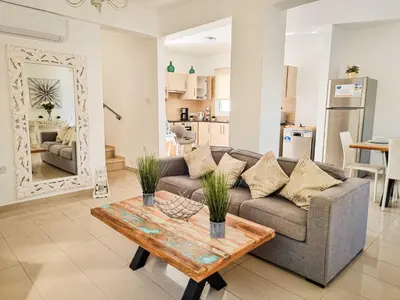 a living room with a couch and a table at Nissi beach villa Magnolia in Ayia Napa