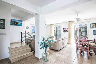 a living room with a staircase and a dining room at Villa Pepper in Protaras