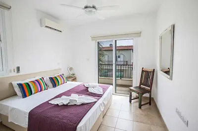 a bedroom with a bed and a chair and a window at Villa Pepper in Protaras