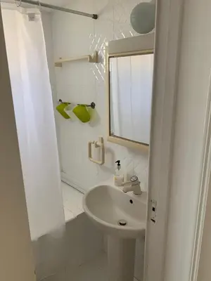 a white bathroom with a sink and a mirror at Seafront Beach House in Meneou