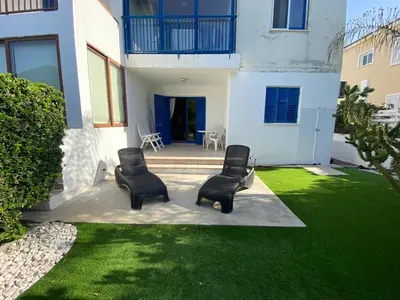 two chairs sitting on a lawn in front of a house at Beach Front Periyiali Gardens in Pervolia