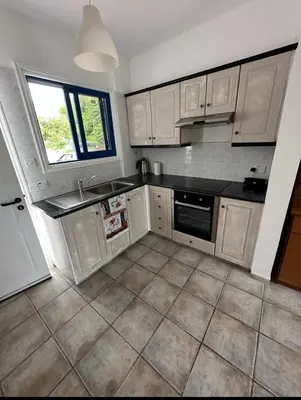 a kitchen with white cabinets and a black counter top at Beach Front Periyiali Gardens in Pervolia