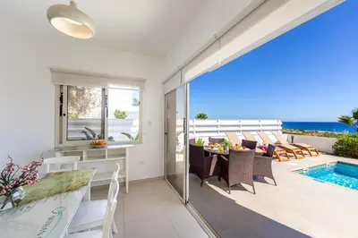 a dining room with a view of the ocean at Protaras Artisan Seafront Villa 1 in Protaras