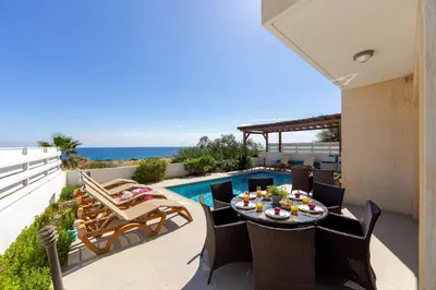 a patio with a table and chairs next to a pool at Protaras Artisan Seafront Villa 1 in Protaras