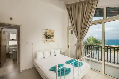 a bedroom with a bed and a balcony with the ocean at Protaras Artisan Seafront Villa 7 in Protaras