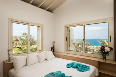 a living room with a white couch and two windows at Protaras Artisan Seafront Villa 7 in Protaras