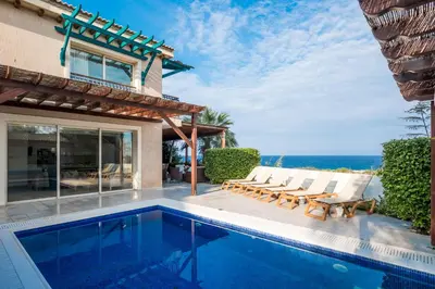 a villa with a swimming pool and the ocean at Protaras Artisan Seafront Villa 7 in Protaras