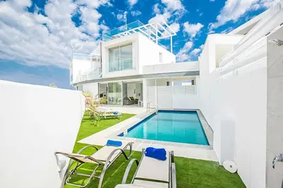 a white house with a swimming pool and chairs at Villa Macan in Protaras