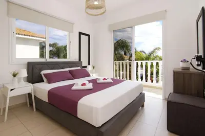 a bedroom with a large bed and a balcony at Nissi Sapphire Villa in Ayia Napa