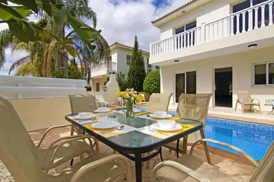a patio with a table and chairs next to a pool at Nissi Sapphire Villa in Ayia Napa