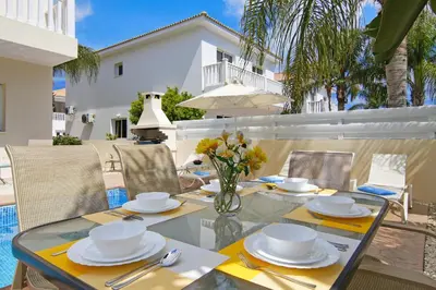 a glass table with plates and utensils on a patio at Nissi Sapphire Villa in Ayia Napa