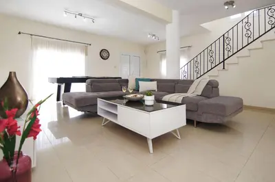 a living room with a couch and a table and a piano at Nissi Adamite Villa in Ayia Napa