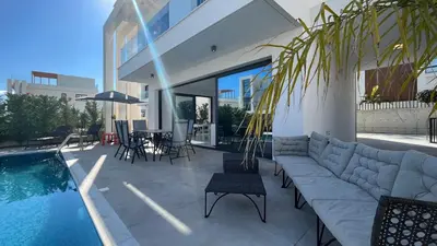 a living room with a couch next to a swimming pool at By the Bay Villa,3 BR/pool in Protaras