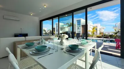 a dining room with a white table and chairs at By the Bay Villa,3 BR/pool in Protaras