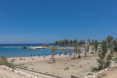 a beach with a bunch of chairs and the ocean at Trinity Villa in Paralimni