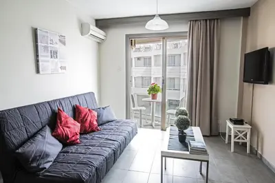 a living room with a black couch with red pillows at Ayia Napa Holiday Apartment So4 in Ayia Napa