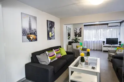 a living room with a black couch and a tv at Ayia Napa Holiday Apartment So3 in Ayia Napa